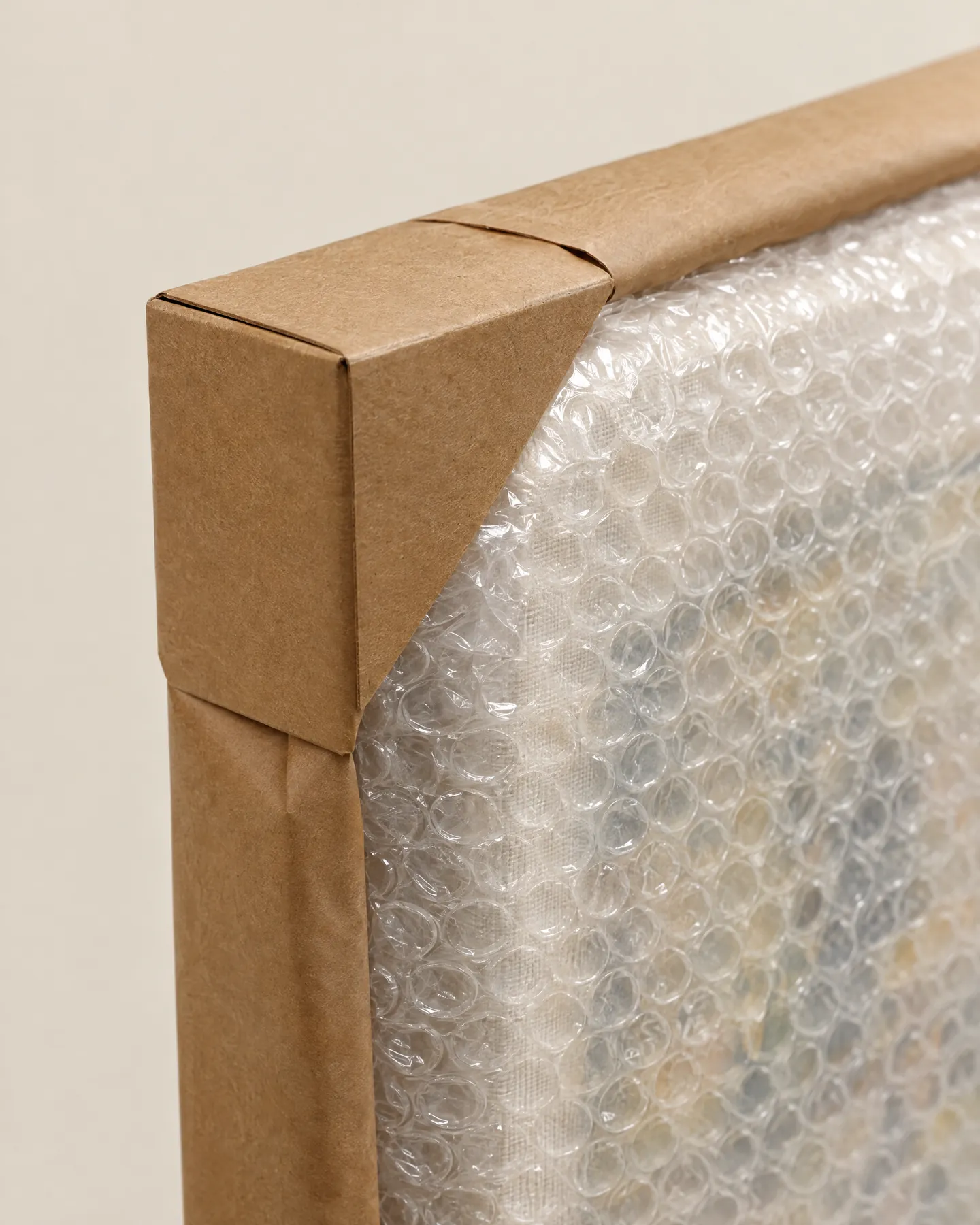 Canvas corner wrapped in bubble wrap with a cardboard corner protector and kraft paper